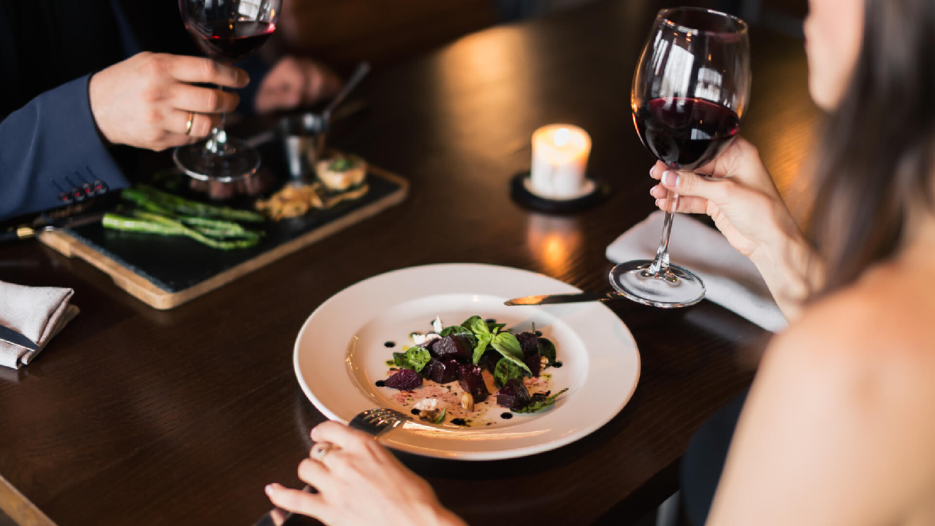 Diners enjoying a meal and a glass of red wine